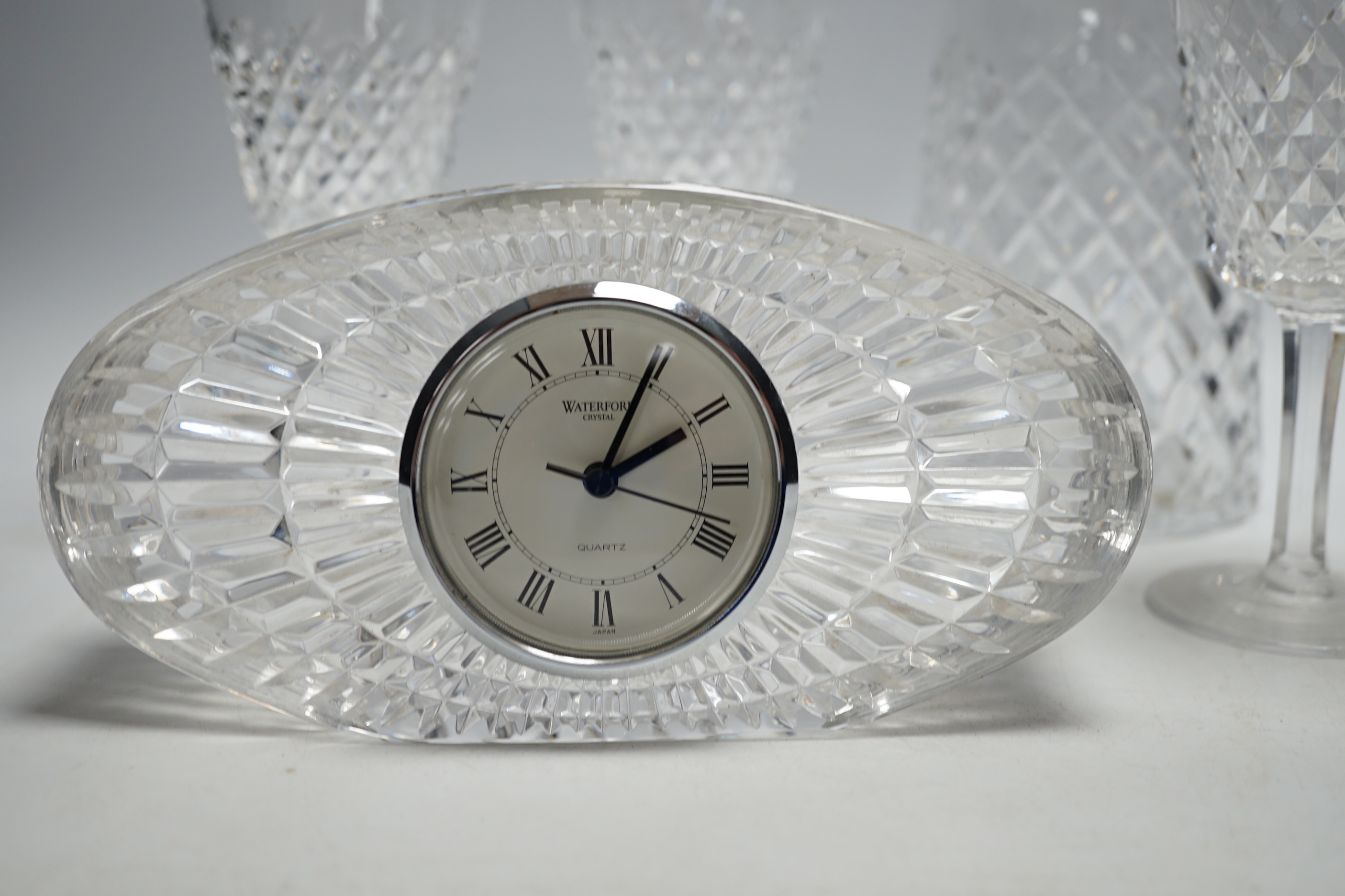 A Waterford cut glass decanter, four glasses and a timepiece